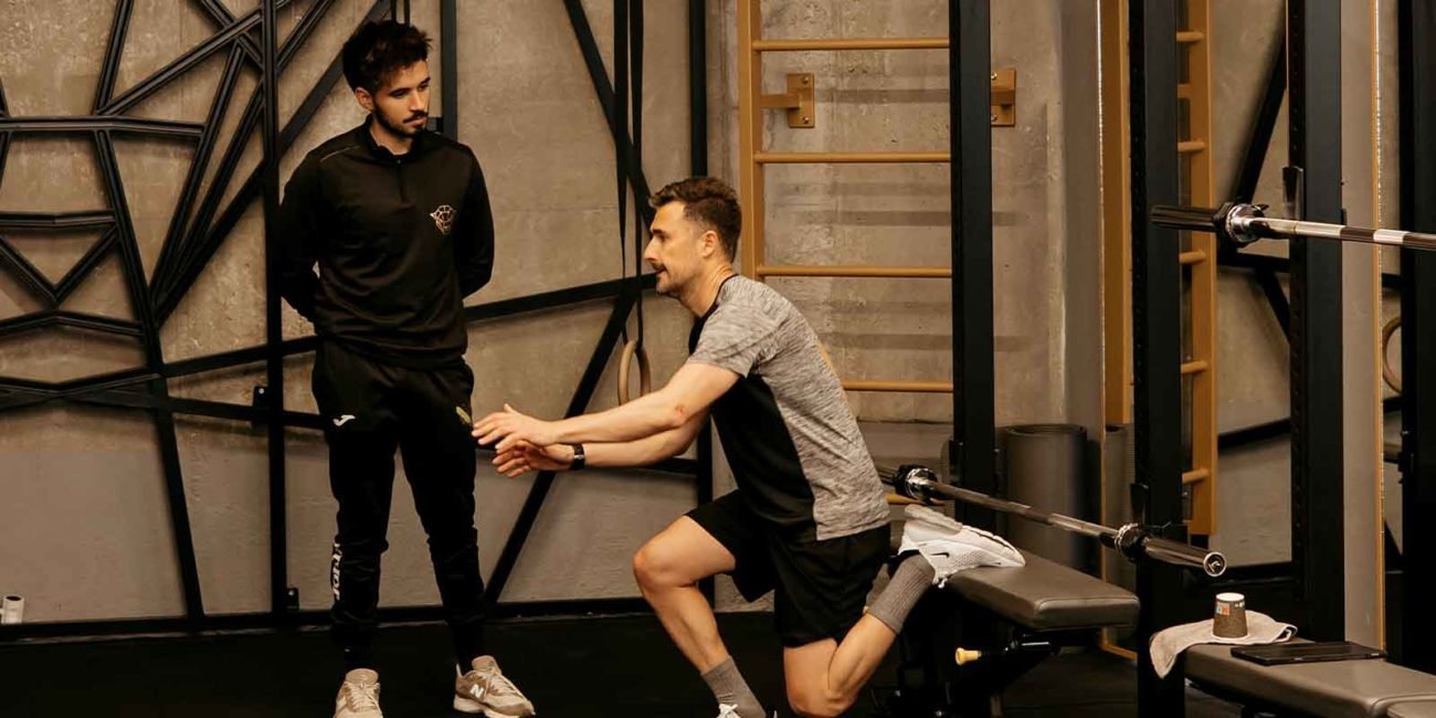 Entrenador personal supervisando a un cliente mientras hace un ejercicio